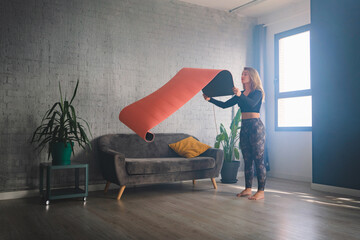 Woman unrolling mat for yoga training