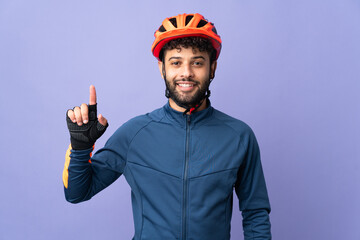 Young Moroccan cyclist man isolated on purple background pointing up a great idea - obrazy, fototapety, plakaty