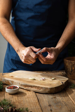 Faceless man peeling garlic in kitchen