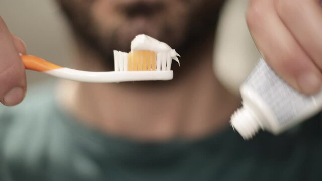 Man hand holding toothbrush and tooth paste tube close up