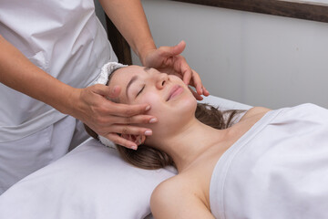 Obraz na płótnie Canvas young woman lying on a stretcher in an aesthetic center performing beauty treatment and facial aesthetics with dermapen and dermaplaning techniques