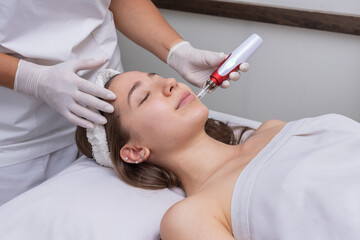 young woman lying on a stretcher in an aesthetic center performing beauty treatment and facial...