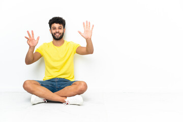 Young Moroccan handsome man sitting on the floor over isolated background counting nine with fingers