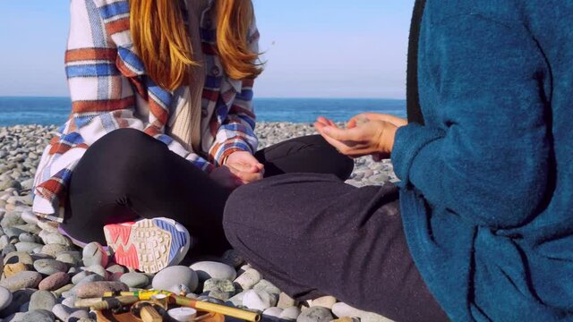 woman pours powder on palm of her hand, wooden tray with Peruvian sacred palo Santo tree, feathers other attributes of rape on pebble beach.Esoteric objects for meditation. Antistress and relaxation