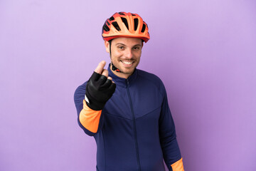 Young Brazilian cyclist man isolated on purple background making money gesture - obrazy, fototapety, plakaty