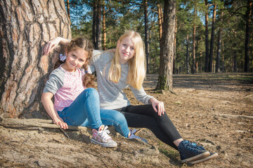 Girls girlfriends sitting together in a pine forest. Nature