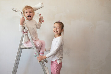 Two girls on ladder painting the wall while one girl shouts with roller in hand - 480423819