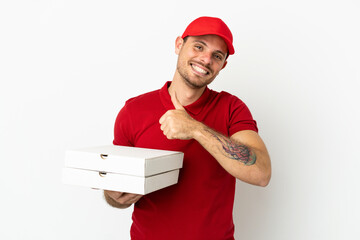 pizza delivery man with work uniform picking up pizza boxes over isolated  white wall giving a thumbs up gesture