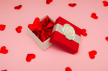 gift box with small red hearts in it on a pink background, close-up, top view. Concept - surprises and gifts for valentine's day. Postcard.