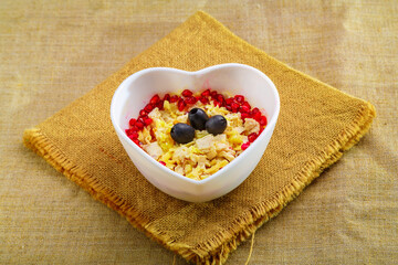 Puff salad with pineapple in a salad bowl decorated with pomegranate on a table on a linen napkin.