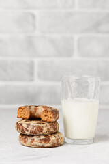 Stack of glazed Russian gingerbread with glass of milk on white table. Round spicy traditional biscuits,  vertical  photo with copy space