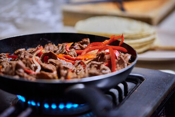 Young man preparing food in shop. Cooking meat with vegetables. frying meat with red peppers,...
