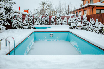Frozen swimming pool under the snow on the back yard.
