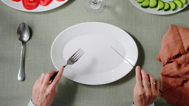 a visitor sits at a table in front of an empty plate in a restaurant and waits for an order. restaurant business concept
