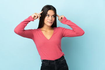 Fototapeta premium Teenager girl isolated on blue background having doubts and thinking