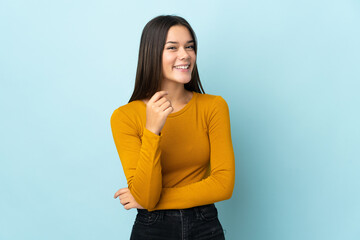 Teenager girl isolated on blue background laughing