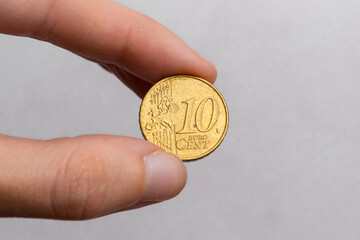 Hand holding a coin of ten euro cents on a white background close-up
