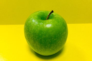 Juicy green apple on a yellow background. Big ripe apple