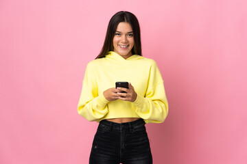 Teenager girl isolated on pink background sending a message with the mobile