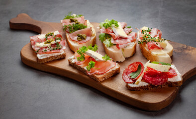 Appetizers table with antipasti snacks or authentic traditional Spanish tapas set, cheese variety board and sour cream, placed on wooden serving board
