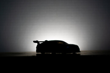 front side silhouette of a sports car being illuminated against a white background 