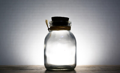 empty glass bottle being illuminated against a white background 