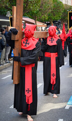 Cofrades penitentes portando una cruz de madera al hombro durante la semana santa de Valladolid,...