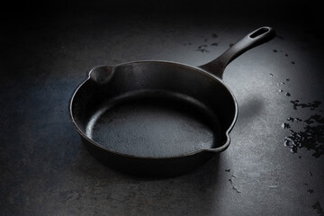 empty cast iron skillet on black background and between shadow .