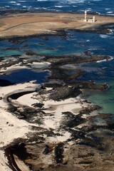 Fotografía aérea de la Caleta del Marrajo y faro del Tostón en la costa de la isla de Fuerteventura, Canarias