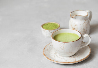 Matcha latte, matcha powder and milk on a gray concrete background. Japanese green tea. Copy space