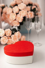 Gift box in the shape of a heart, a bouquet of roses and champagne glasses. Valentine's Day - February 14th. light background