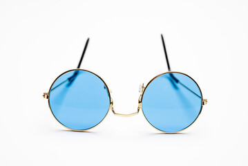 Fototapeta premium Sunglasses with blue color lens and gold round metal frame isolated on white background