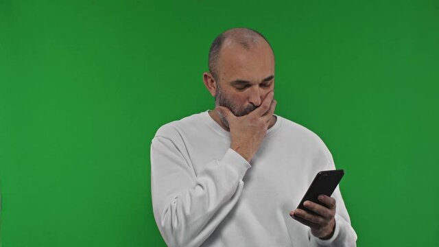 Mature mid aged man using a phone. Portrait of a mature white man texting in front of green screen.