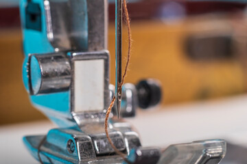 sewing machine. a foot and a needle with a thread in the center of attention. close-up. there is a slight tinting of the frame