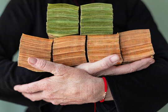 Bundles of 500 and 1000 Argentine pesos held in woman's arms