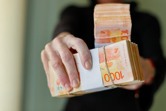Macro closeup of bundles of 1000 Argentine peso bills held by woman's hands