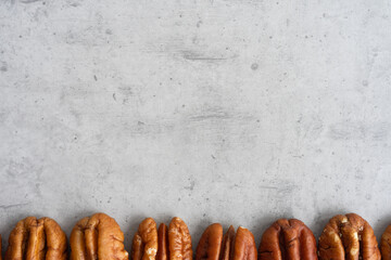 Row of pecans below on a gray background, close-up - obrazy, fototapety, plakaty