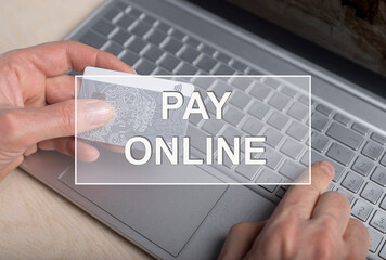 Pay online text on photo with bank card and laptop.