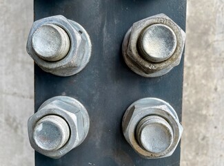 Close up of big screws and nuts on stale plate, concrete background. Industrial concept.