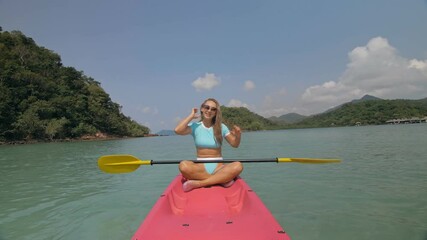 Sportive woman rows pink plastic canoe along sea water.