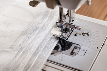 The process of sewing with curtain tape on a sewing machine close-up.