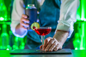 Bartender's hands serving cocktails on bar counter in a restaurant, pub. Mixed drinks. Alcoholic cooler beverage at nightclub on dark background