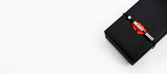 Valentines Day gift wrapping, package. Valentines Day gift background with black craft gift box with text I Love you and two red paper hearts.