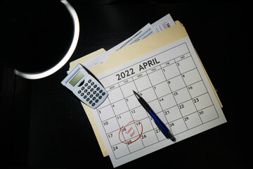 Concept of 2021 Tax preparation documents and calender with April 18th circled on black background.