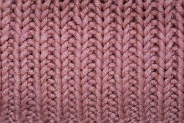 Knitting needles. The product is crocheted of pink woolen threads. Knitted pink background. Handmade knitwear texture.