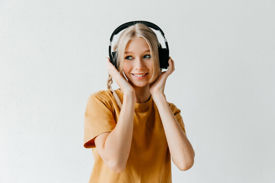 Happy Young Woman Wearing In Black Headphones And Smiling On White Background