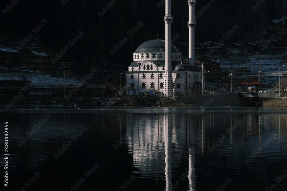 Wall mural Reflection of white mosque, islamic mosque and its reflection on water and pond of a lake uzungol in Trabzon during winter season.