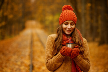 Young woman drinking tea in autumn park