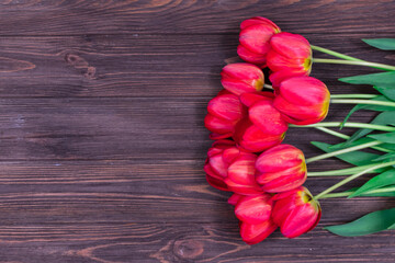 Red tulips on a brown wooden background. Mothers Day. March 8. Place for an inscription. The basis for the postcard.