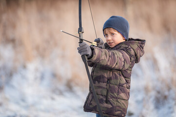 Portrait of a young boy shooting a bow.